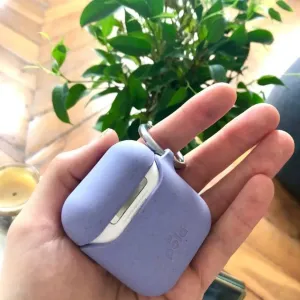 Pela lavendelfärgat komposterbart fodral för AirPods med nyckelring, visat delvis öppet i handen
