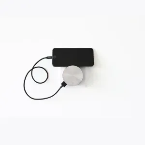 Usbepower AERO Mini Luxury Edition väggladdare med telefonställ, visad när den laddar en smarttelefon med USB-kabel