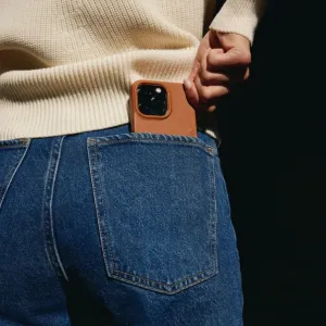 Mujjo Full Leather Case med MagSafe på en iPhone 14 instoppad i bakfickan på ett par jeans