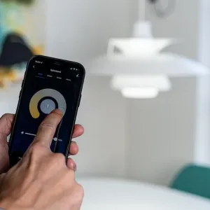 Lite Bulb Moments smartlampa styrs i appen, med en hänglampa som visas i bakgrunden.