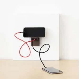 Usbepower Rock Dual USB-A-laddare monterad på väggen med anslutna kablar som laddar en smartphone