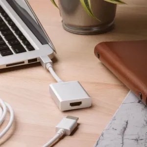 Moshi vit HDMI-kabel ansluten till en bärbar dator och adapter på ett skrivbord, för 4K-hemmabiouppsättningar