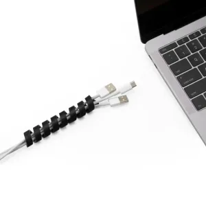 Bluelounge CableCoil kabelorganiserare med två laddningskablar lindade bredvid en bärbar dator, i svart