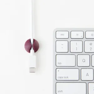 Bluelounge CableDrop Mini-kabelhanteringsklämma fäster en vit kabel bredvid ett tangentbord