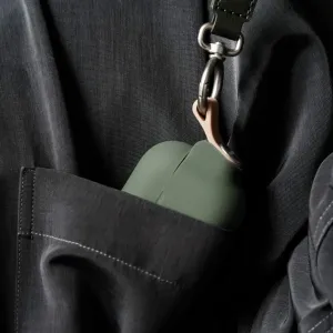Moshi Pebbo-fodral för AirPods Pro 2 med handledsrem fäst på mörka kläder, grön finish