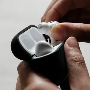 Moshi Pebbo AirPods Pro 2-fodral i Shadow Black, visas öppet medan en vit öronsnäcka sätts in för hand