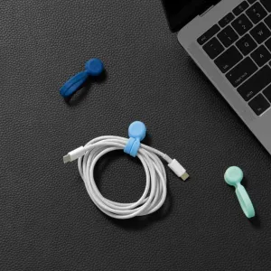 Bluelounge MagWrap liten magnetisk kabelhållare som håller en ihoprullad vit USB-C-kabel på plats bredvid en bärbar dator