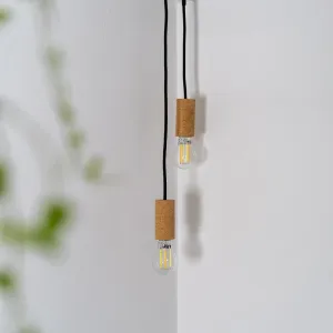 Lite Bulb Moments klara E27-filamentlampor med korkfärgade lamphållare hänger i svarta sladdar mot en vit vägg.