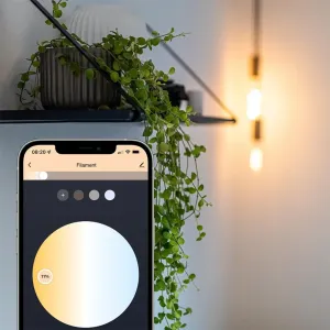 Lite Bulb Moments E27-filamentlampa som lyser varmvitt bredvid en mobilapp med färgkontroller