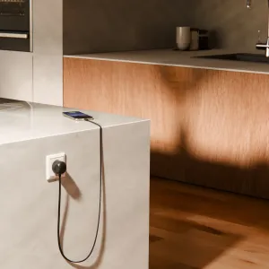 Twelve South PowerCord USB-C-laddare ansluten till ett vägguttag, laddar en smartphone på en bänkskiva.