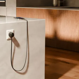 Twelve South PowerCord 3 m svart flätad laddningskabel ansluten till ett vägguttag, laddar en telefon