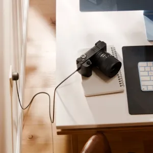 Twelve South PowerCord 3 m svart integrerad laddare med lång kabel som driver en kamera på ett skrivbord