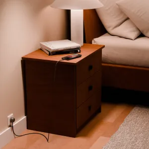 Twelve South PowerCord 3 m laddar en smartphone bredvid ett nattduksbord i en varm sovrumsmiljö