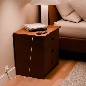 Twelve South PowerCord USB-C-laddare på ett nattduksbord, med en vit kabel ansluten till ett EU-uttag.
