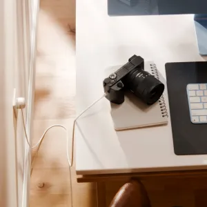 Twelve South PowerCord vit USB-C-laddningskabel inkopplad i ett vägguttag bredvid en skrivbordsuppställning