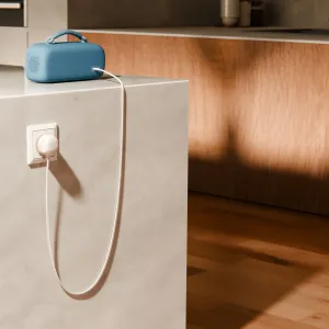 Twelve South powerCord vit flätad kabel ansluten till en blå högtalare bredvid ett vägguttag