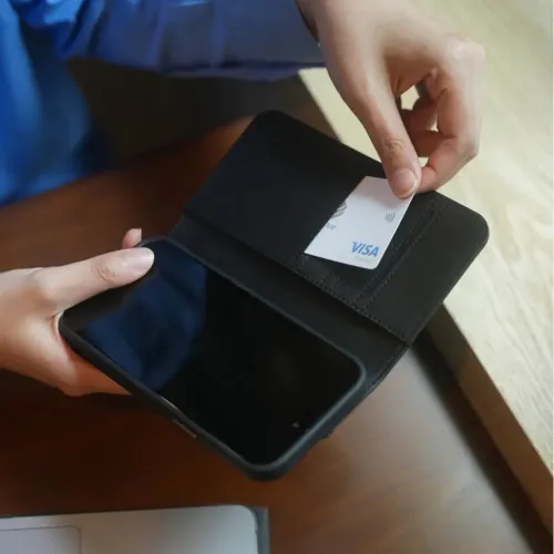Moshi Overture iPhone 15 Pro Max-fodral i foliostil, öppet med kortfack och smarttelefon, visas med ett VISA-kort.