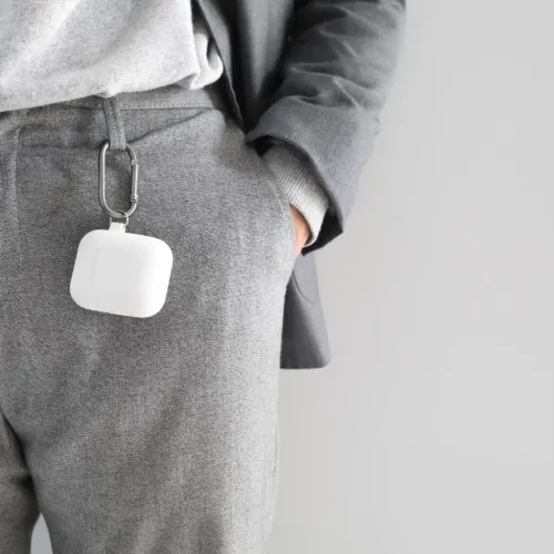 KeyBudz PodSkinz nyckelring AirPods-fodral fäst på grå byxor med karbinhake för portabelt skydd