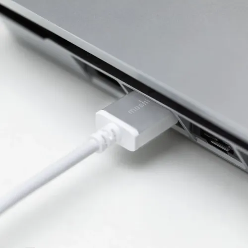Moshi vit HDMI-kabel ansluten till en grå enhet, visad i närbild på en vit yta.
