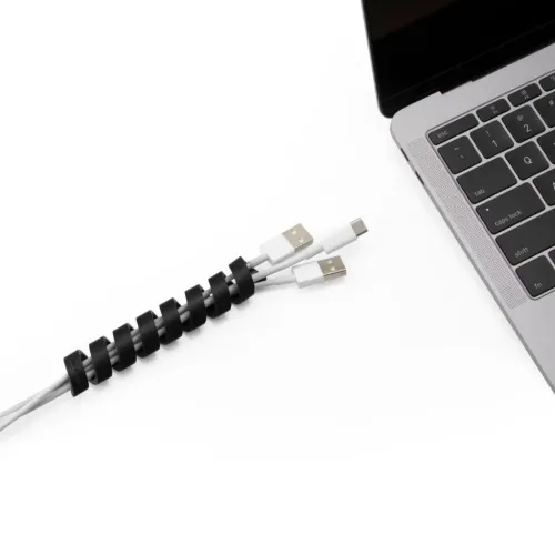 Bluelounge CableCoil kabelorganiserare med två laddningskablar lindade bredvid en bärbar dator, i svart