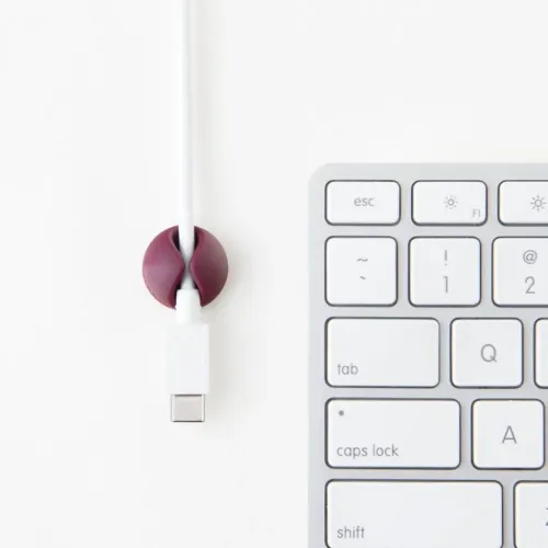 Bluelounge CableDrop Mini-kabelhanteringsklämma fäster en vit kabel bredvid ett tangentbord