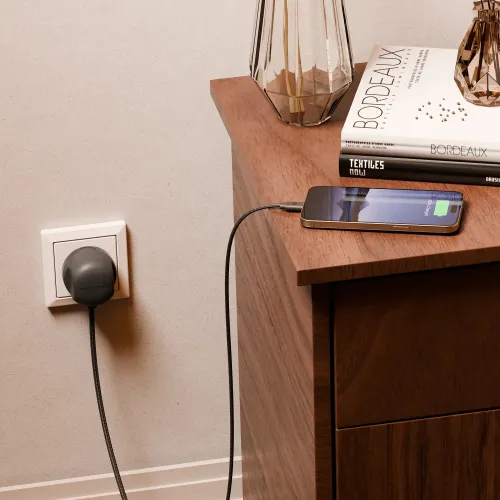 Twelve South PowerCord 3 m flätad USB-C-laddare som laddar en smartphone bredvid ett nattduksbord i trä