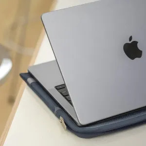 Housse pour ordinateur portable Moshi Pluma 14 pouces avec un MacBook argenté partiellement inséré dans un étui bleu foncé à fermeture éclair
