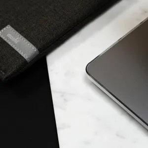 Housse pour ordinateur portable de marque Moshi à côté d’un MacBook Pro gris foncé sur une surface en marbre