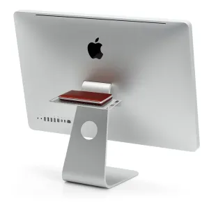 Estante Twelve South BackPack 3 montado en la parte trasera de un iMac, que sostiene un pequeño accesorio rojo.