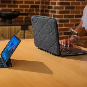 Funda para portátil Twelve South SuitCase para MacBook Pro de 16 pulgadas en gris oscuro, abierta alrededor de un MacBook sobre una mesa.