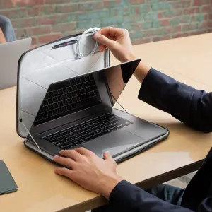 Funda rígida acolchada gris Twelve South SuitCase con un MacBook Pro/Air de 15"/16" en el interior, abierta sobre una mesa.