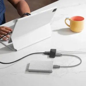 Concentrador USB-C Twelve South StayGo mini conectado a una tableta sobre un escritorio, con dos cables conectados.