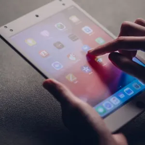 Moshi iVisor AG protector de pantalla antirreflejos para iPad mini 5, mostrado en uso con una mano sobre la pantalla táctil