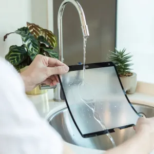 Protector de pantalla Moshi iVisor AG para iPad 10,2 enjuagándose bajo el agua, mostrando un diseño lavable y reutilizable