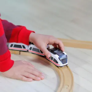 Adaptateurs pour rails en bois Intelino utilisés avec un train jouet sur un rail en bois incurvé, guidé par la main d’un enfant