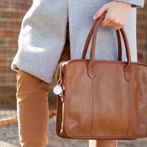 Rastreador adhesivo Orbit fijado a una bolsa de piel marrón, mostrado como un rastreador discreto para bolsos.