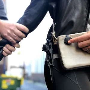 Alarma personal Orbit Protect sujeta a una riñonera beige, llevada por una persona al aire libre.