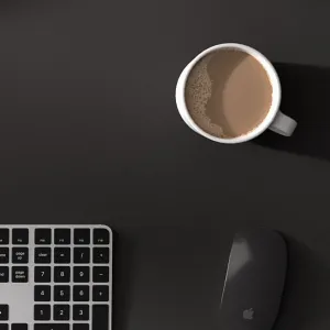 Twelve South deskPad svart skrivbordsmatta i veganskt läder med tangentbord, mus och kaffe på en arbetsyta