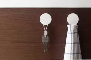 Élastiques Bluelounge Pixi avec verrou utilisés sur des crochets muraux pour suspendre des clés et un torchon à carreaux