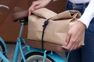 La bande élastique Bluelounge Pixi maintient un colis emballé dans du papier sur une selle de vélo pour faciliter le transport