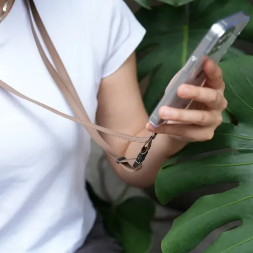 Moshi 2-i-1 handleds-/kroppsrem i Woodsmoke Brown fäst vid en smartphone, buren över kroppen