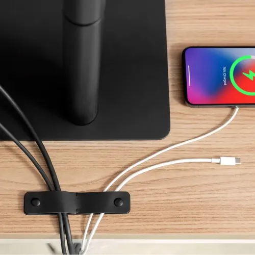 Twelve South CableSnap Stay organiza cables con pinzas sobre un escritorio, junto a un smartphone cargándose.