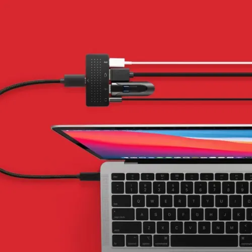 Twelve South StayGo mini USB-C-Hub, an einen Laptop angeschlossen, mit mehreren Kabeln auf rotem Hintergrund.