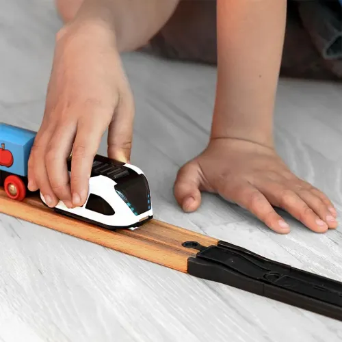 Les adaptateurs pour rails en bois Intelino relient un train jouet à des rails en bois dans une scène de jeu pour enfant