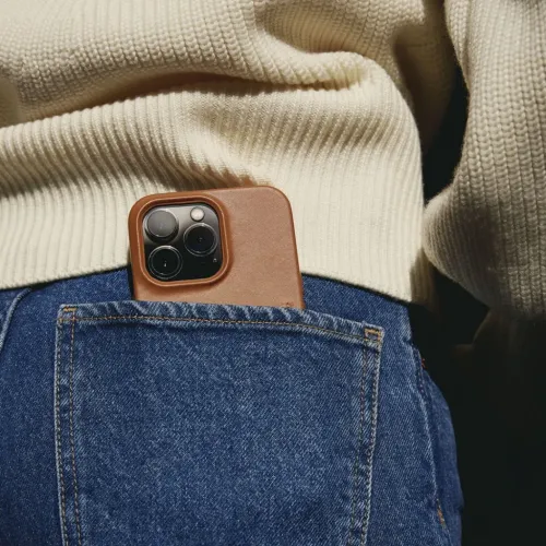 Mujjo Full Leather Wallet Case für iPhone 14 Pro Max aus braunem Leder, in die Hosentasche einer Jeans gesteckt, mit Kameraaussparung.
