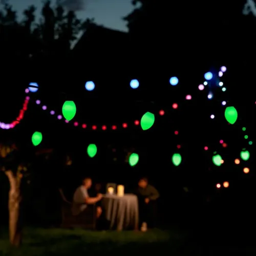 Lite Bulb Moments smarte Outdoor-Lichterkette mit kugel- und kegelförmigen Leuchten und farbigen Kugellampen bei Nacht
