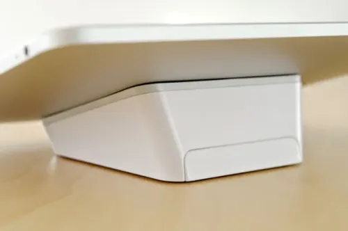 Soporte para tablet Bluelounge Casa sobre una mesa de madera, con diseño en cuña blanco y soporte de dos ángulos.