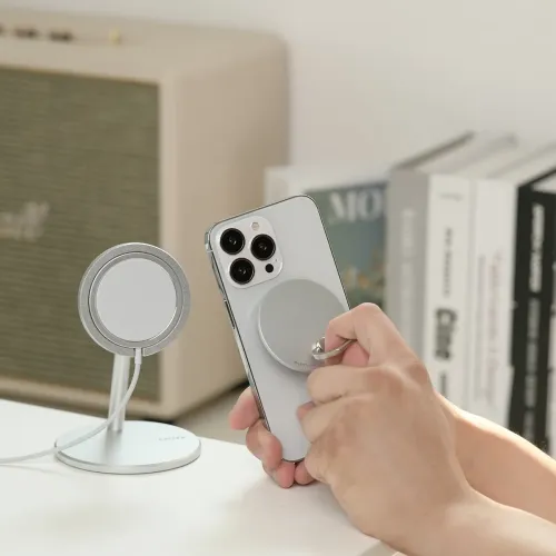 Agarre magnético para teléfono iRing Mag plateado, sujeto a un smartphone junto a un soporte de escritorio a juego