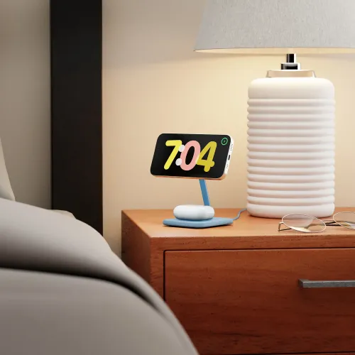 Twelve South HiRise 2 Deluxe laddningsställ för trådlös laddning som håller en smartphone på ett sängbord bredvid en lampa.