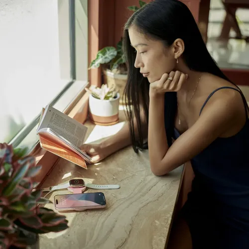 Twelve South Butterfly™ SE pinkes kabelloses Ladegerät mit einem iPhone und einer Apple Watch auf einer Tischplatte